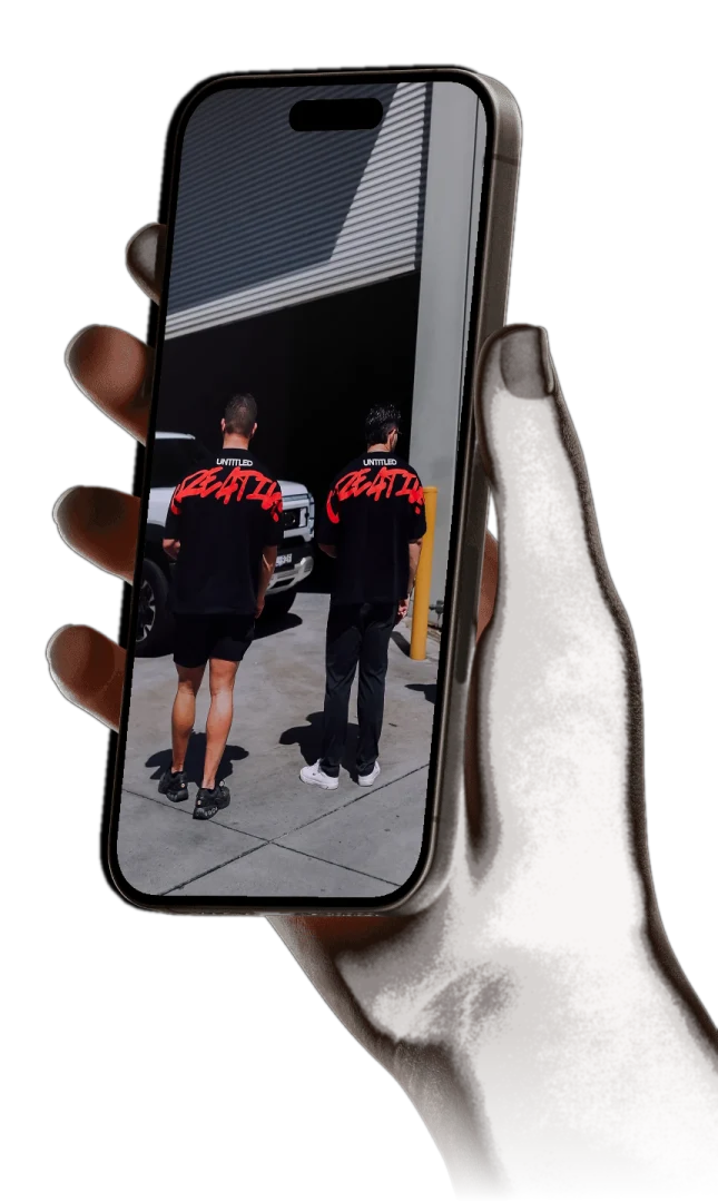 Hand holding a phone showing the Untitled Creative team in branded shirts